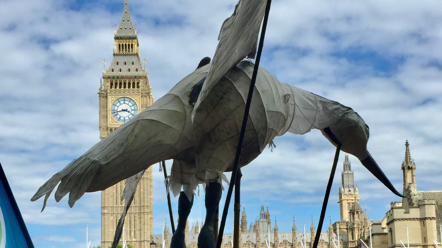 Model of white sea bird held up by crowds at Houses of Parliament
