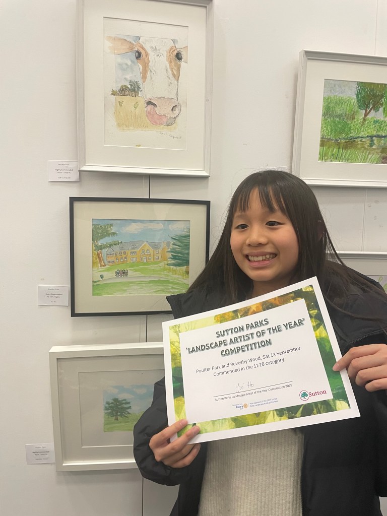 Yui Ho holds her certificate in front of her picture hung in the gallery show